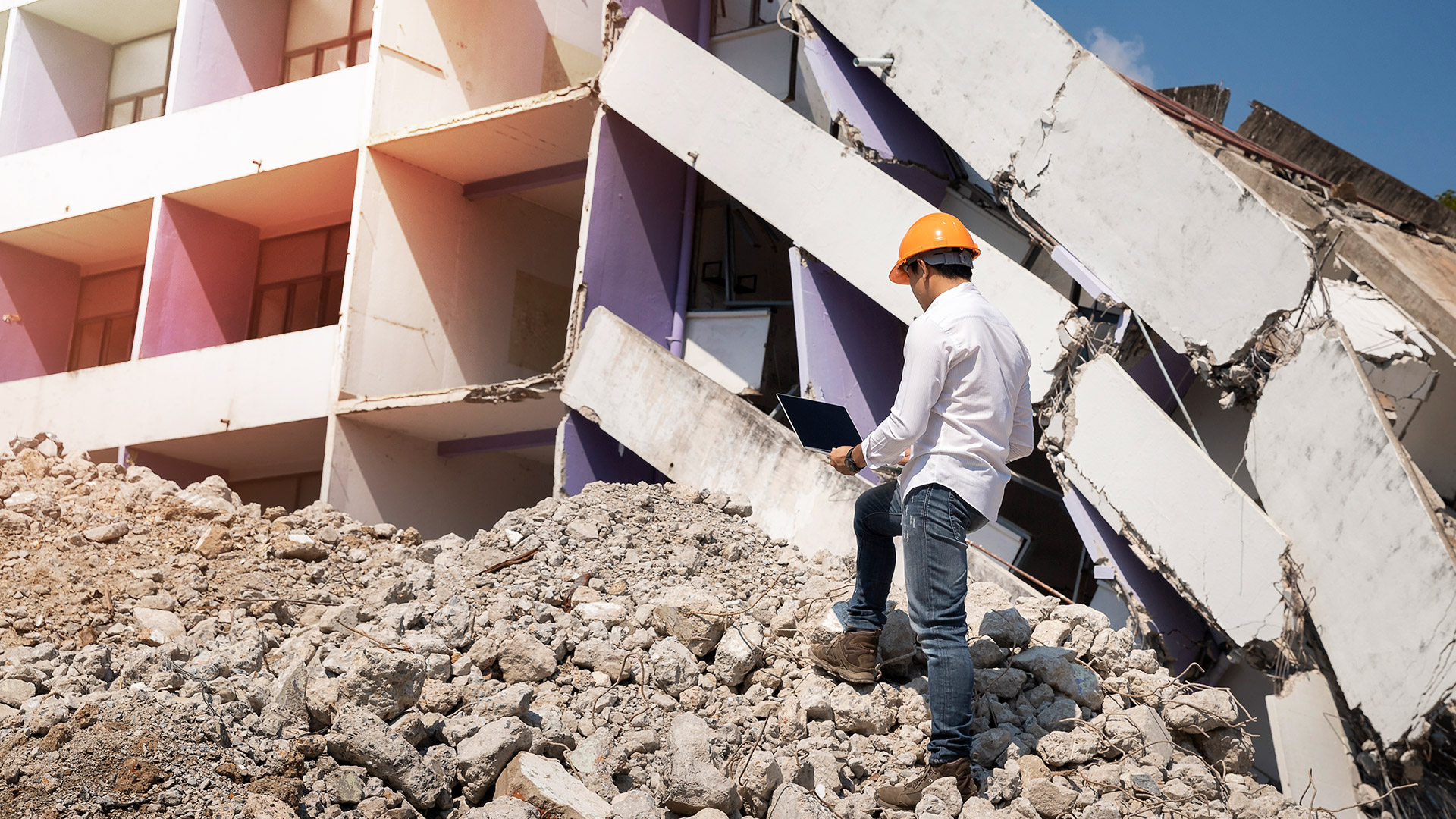 An engineering professional documenting a damaged building with a laptop