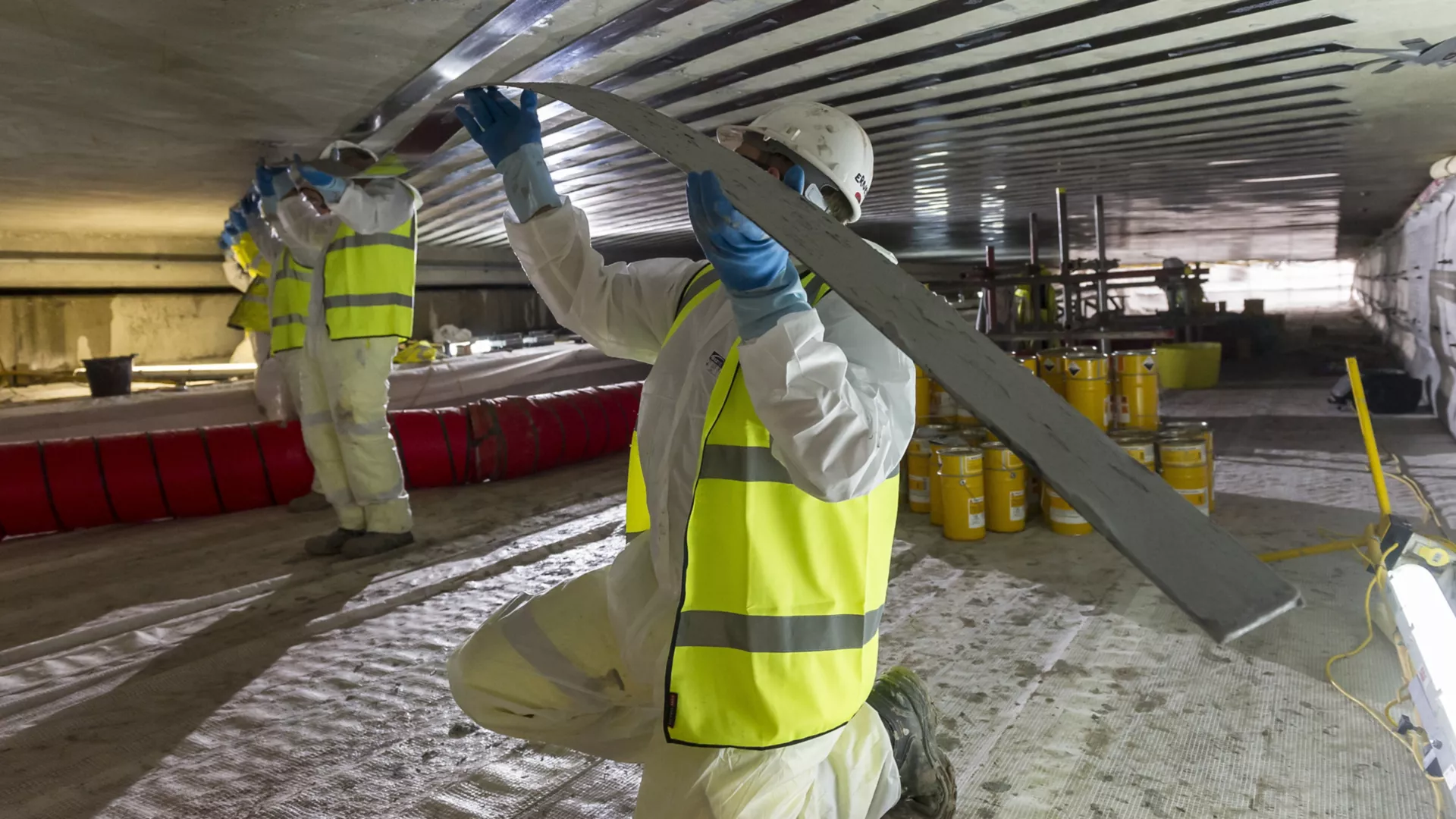 Workers in protective equipment installing strengthening strips beneath a concrete slab